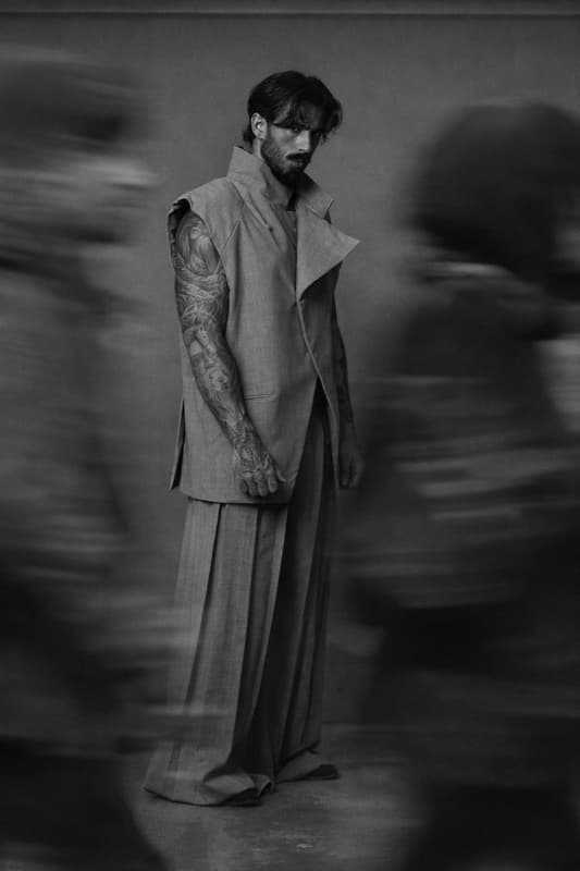 Campaign — a still figure in a structured vest as blurred passers-by move around him