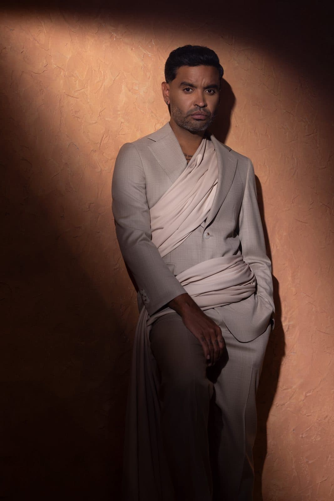 A pale grey jacket wrapped and draped across the body over dark trousers