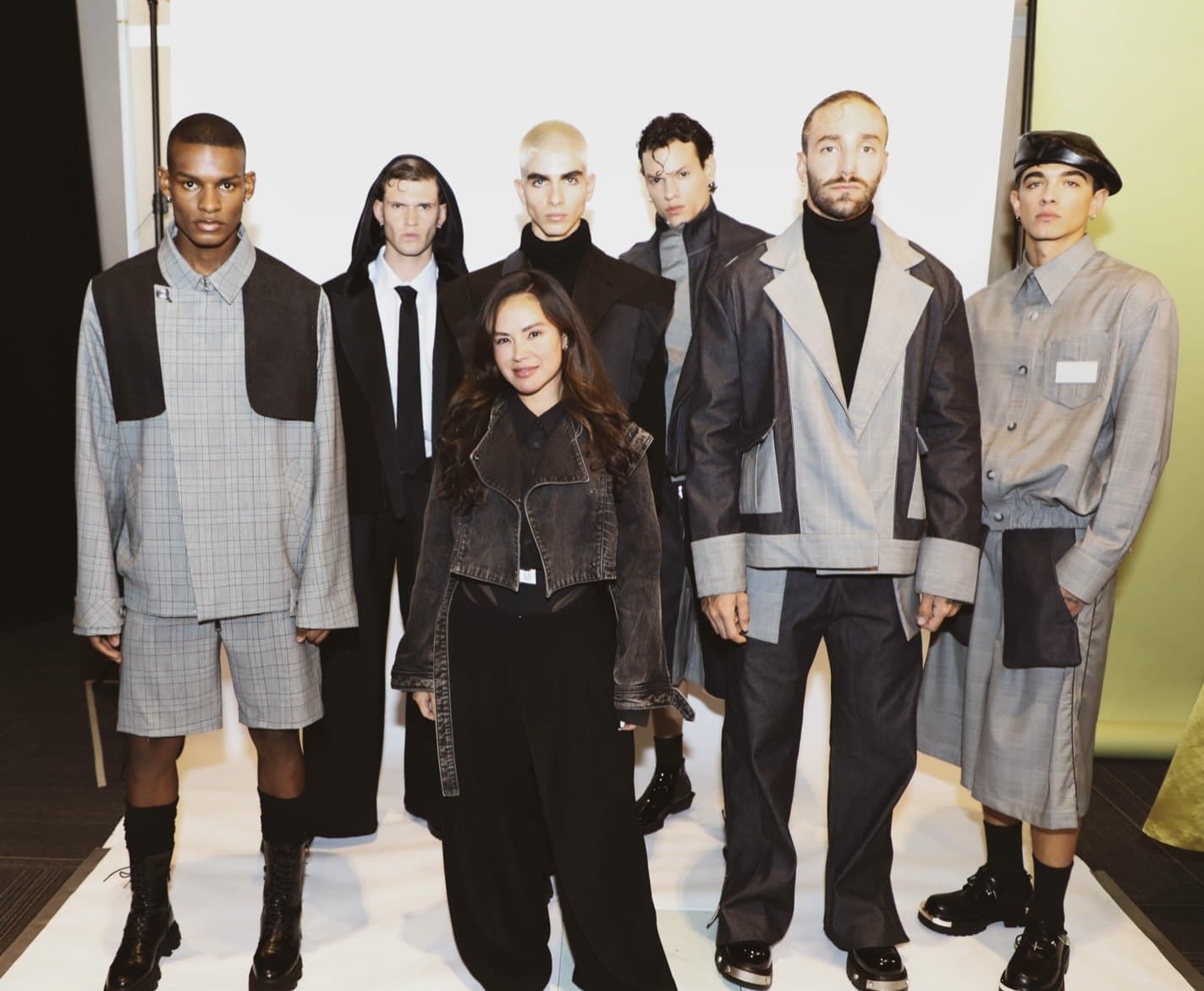 Paloma Balvin standing at the center of six models wearing her grey tailored menswear collection