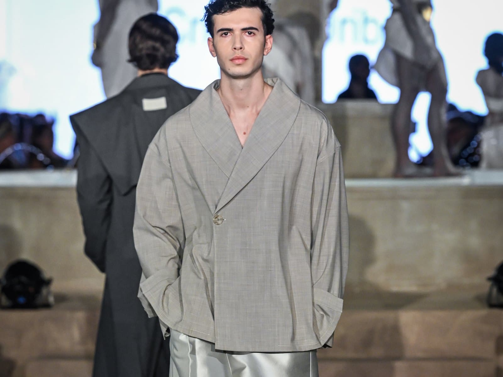 Runway moment — an oversized shawl-collar jacket in grey check worn over satin tailored shorts