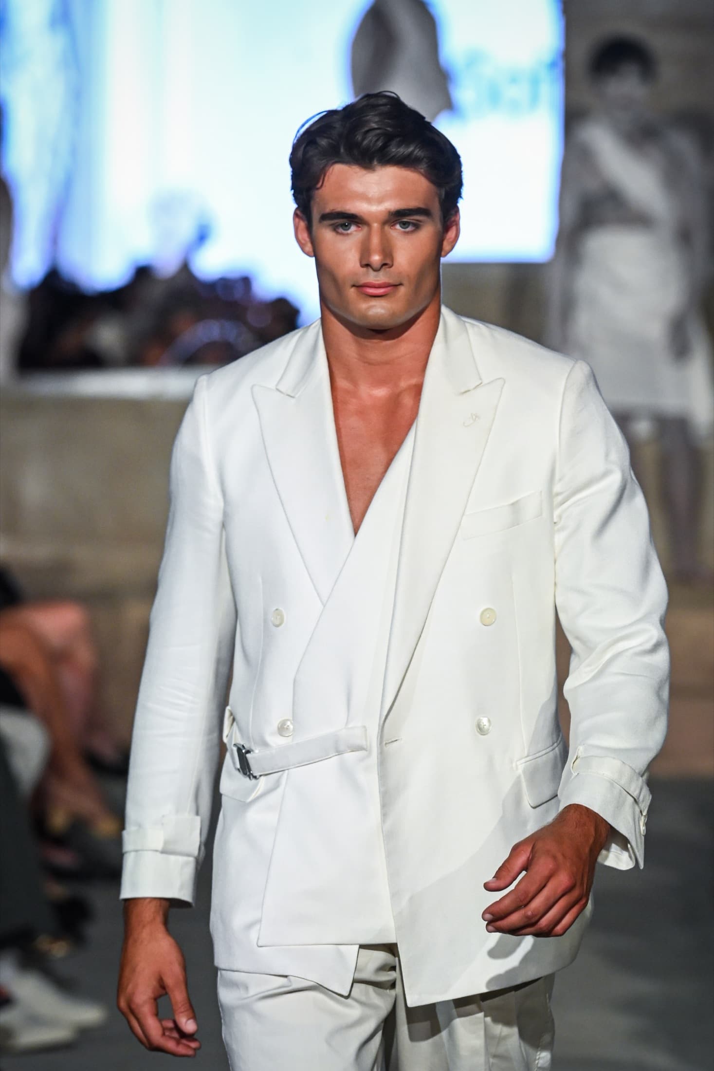 Model in a white double-breasted belted jacket walking the runway — Miami Design District