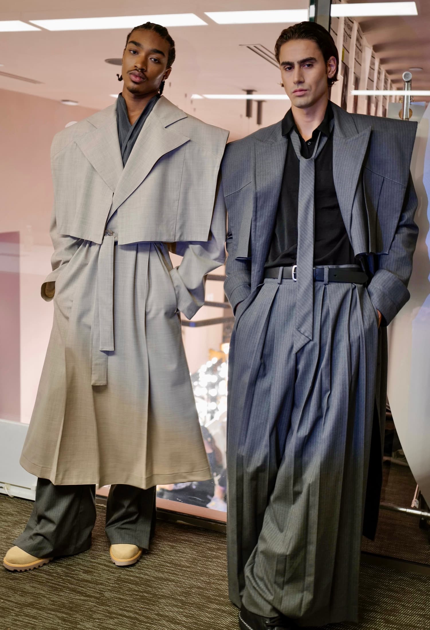 Two models backstage in the greige layered coat and the charcoal suit — Miami Design District