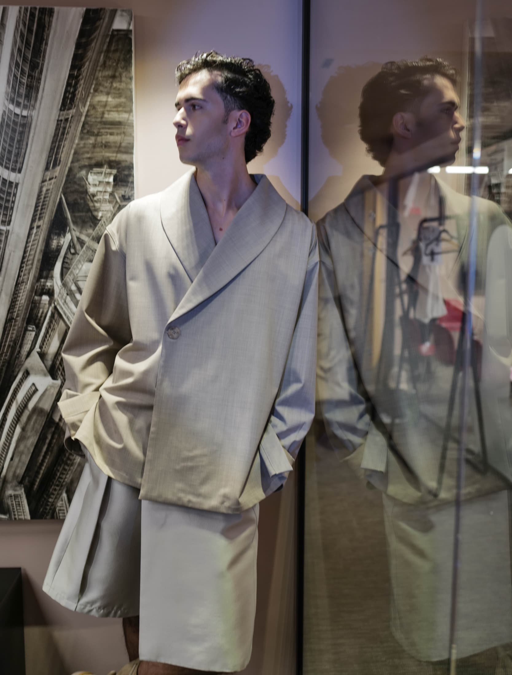 Model in the greige shawl-collar jacket reflected in a glass partition — Miami Design District