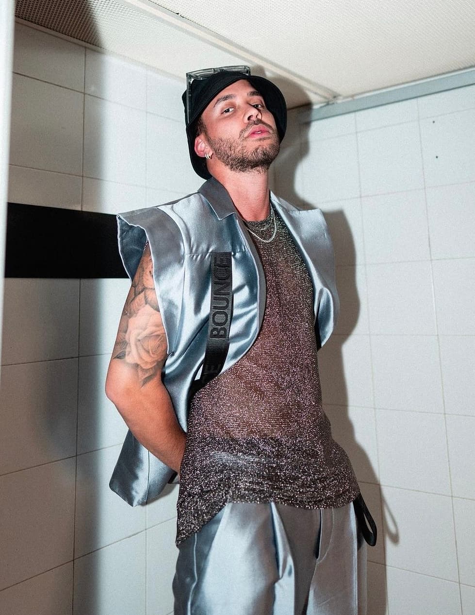 A silver satin sleeveless vest worn over a metallic mesh top with matching trousers