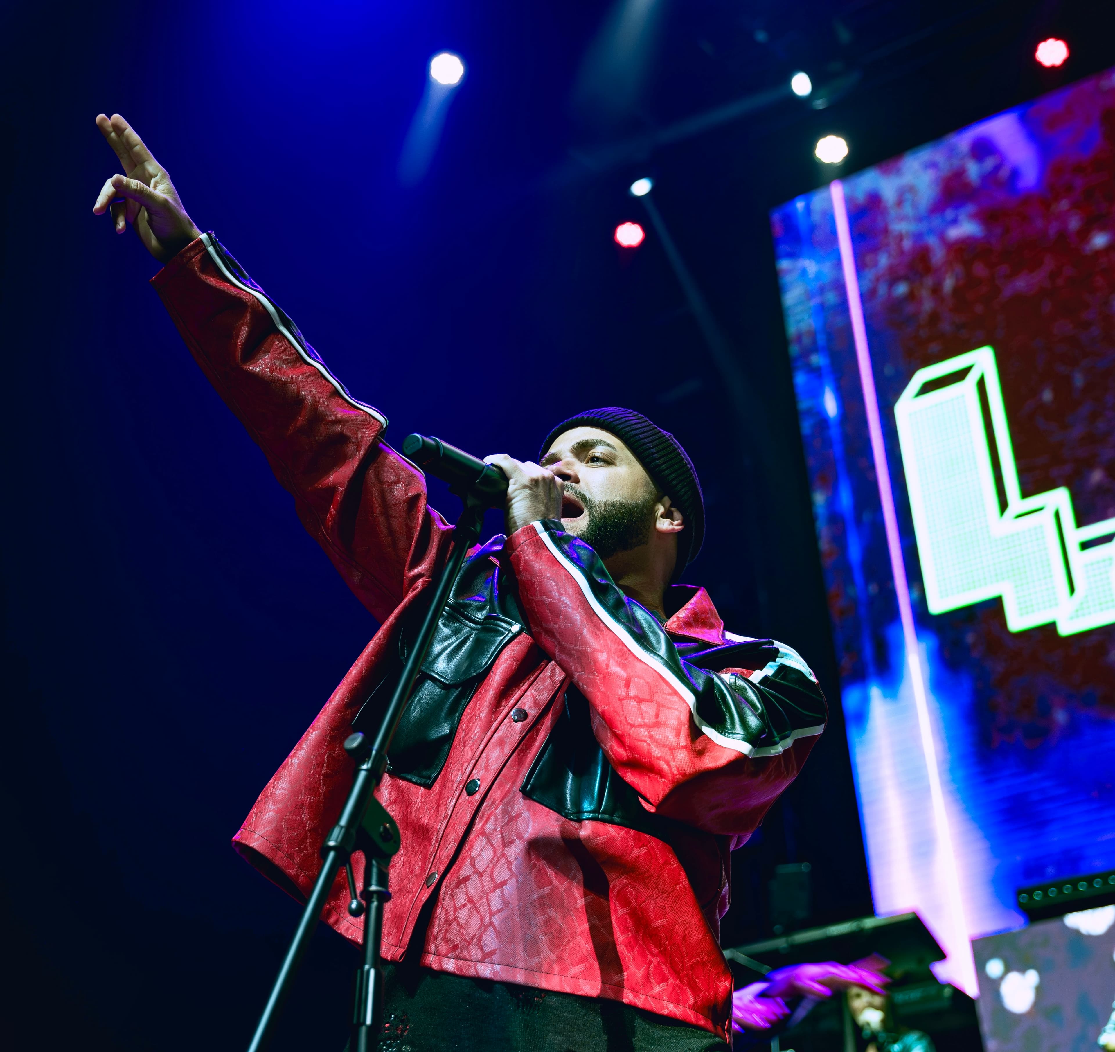 A red croc-embossed jacket panelled into black, worn under stage light