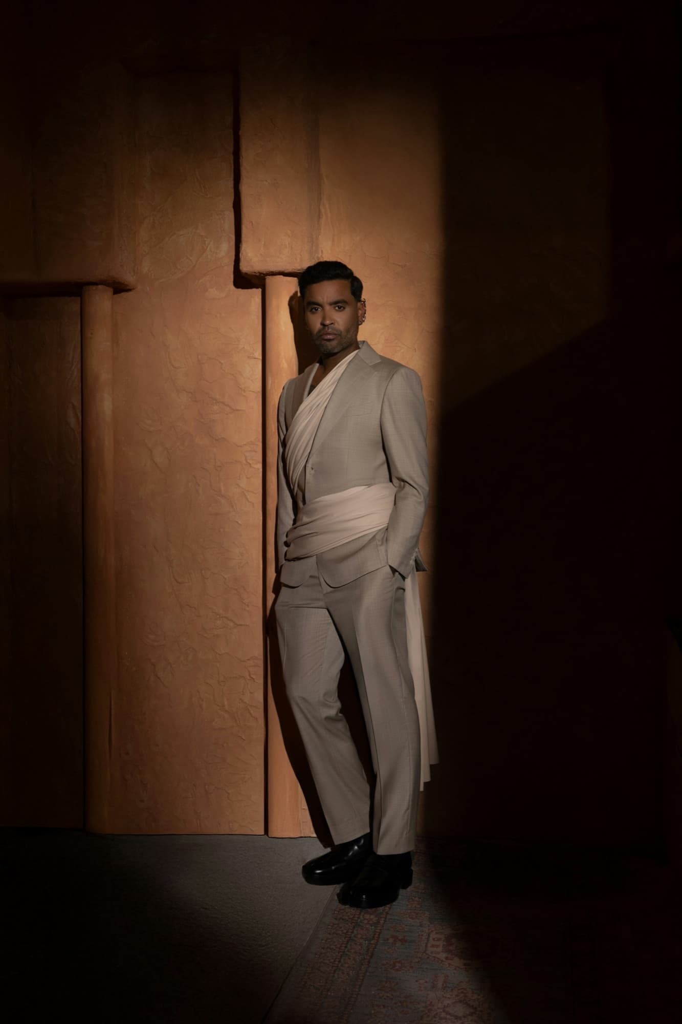 Zion in draped tailoring, standing in a shaft of light — styled by Paloma Balvin