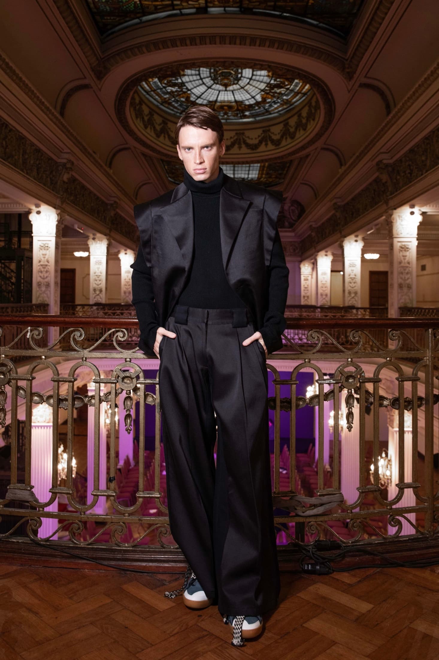 Profile view of a model in black satin tailoring in a gilded theatre — Argentina Fashion Week