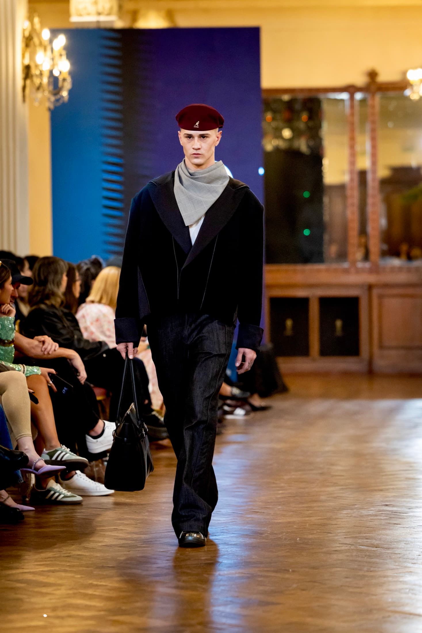 Model in a red beret and grey scarf over a black cropped jacket, carrying a black bag — Argentina Fashion Week